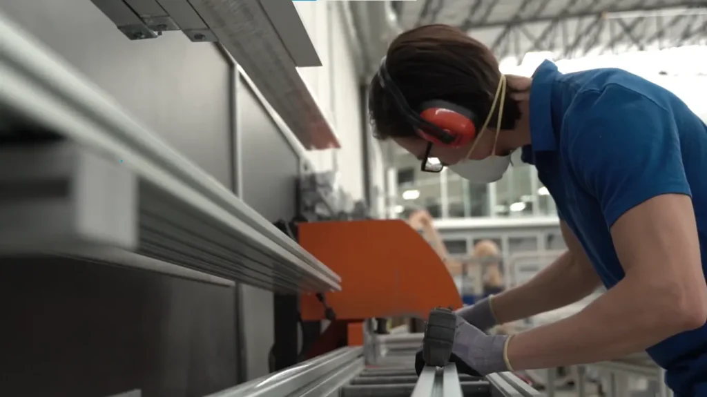 colaborador midiendo un perfil de aluminio, portando su equipo de seguridad