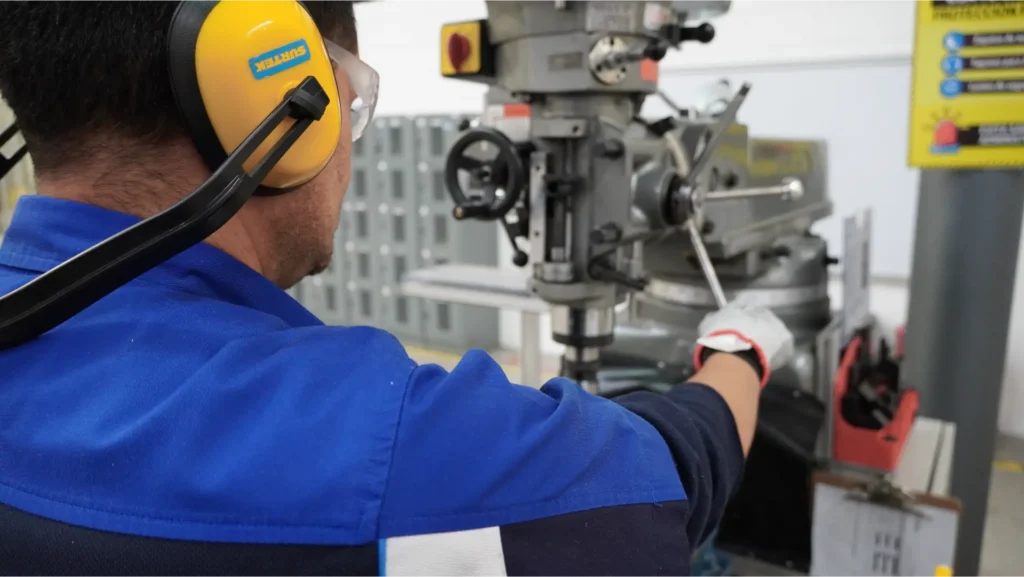 colaborador operando una máquina de barrenado, siguiendo protocolos de seguridad industrial